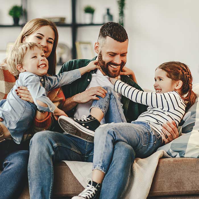 general-dentistry-feature-square happy family mother father and kids at home on couch